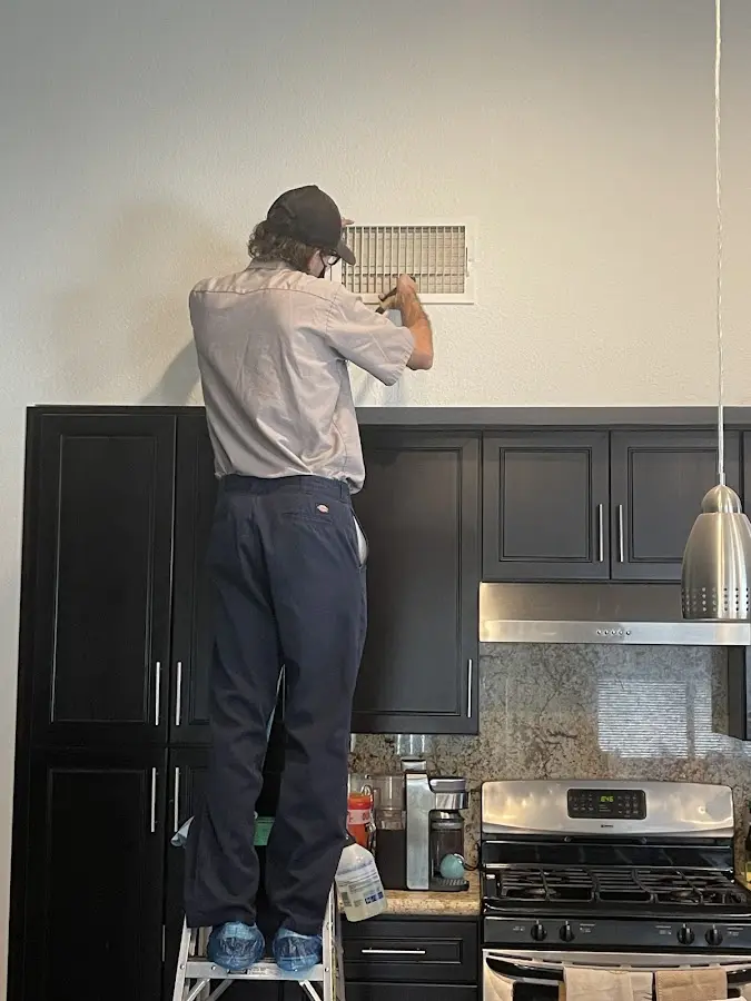Technician inspecting an air vent during HVAC service in Sergeant Bluff